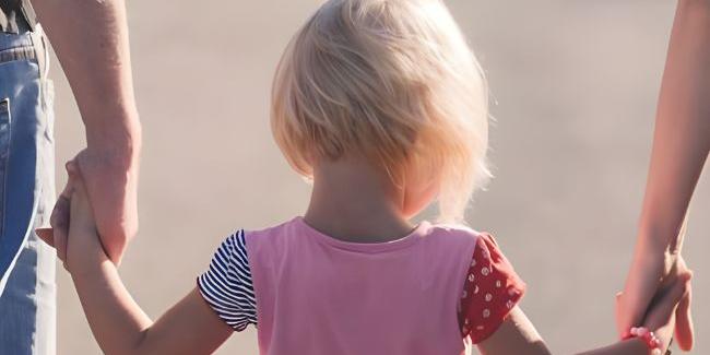 Kind an der Hand zweier Erwachsener