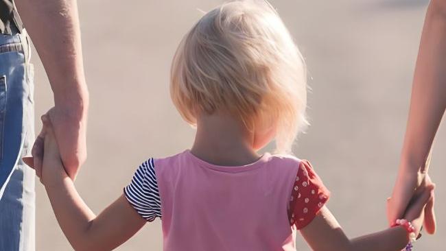 Kind an der Hand zweier Erwachsener