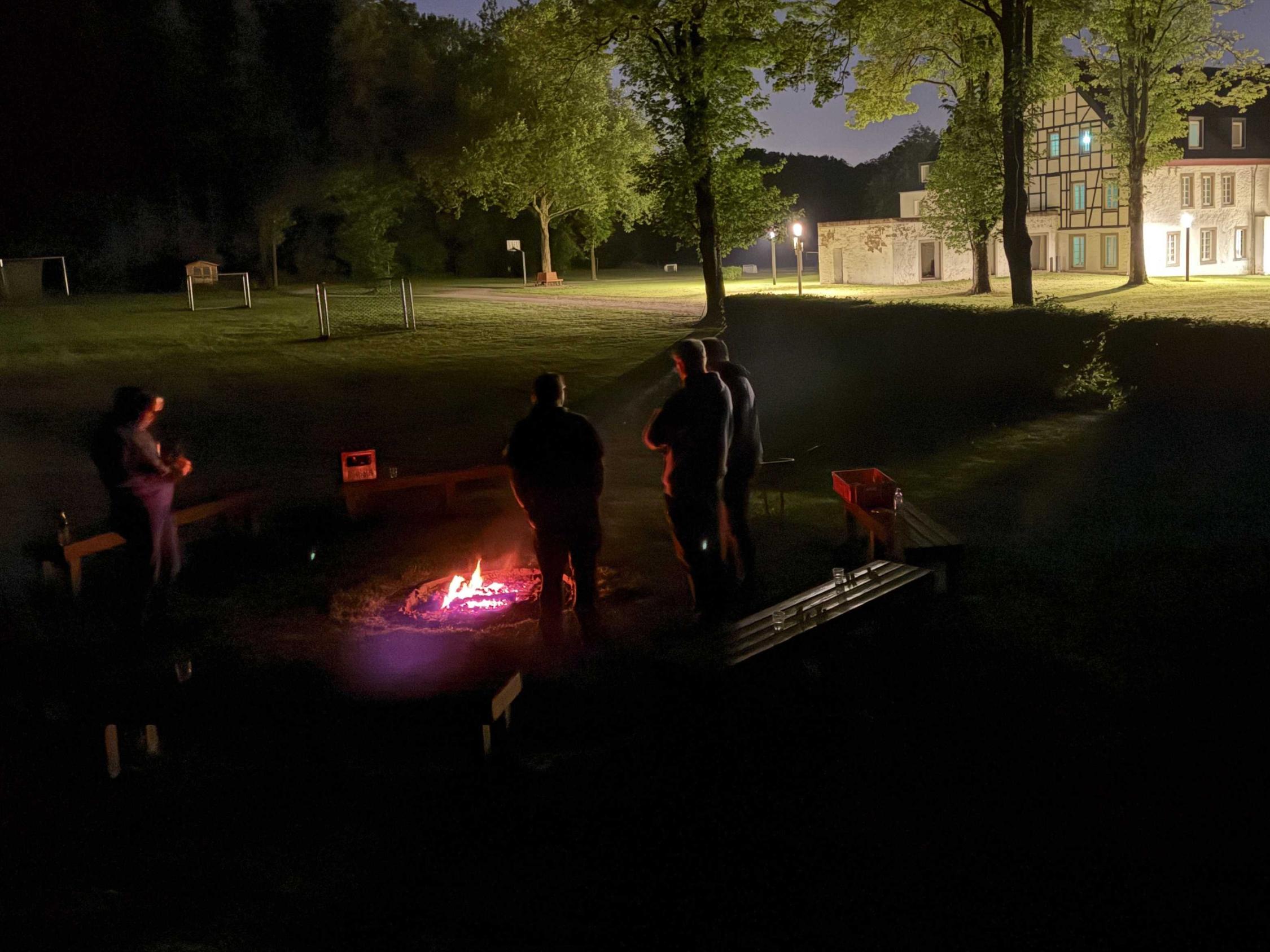 Männer stehen um ein Lagerfeuer