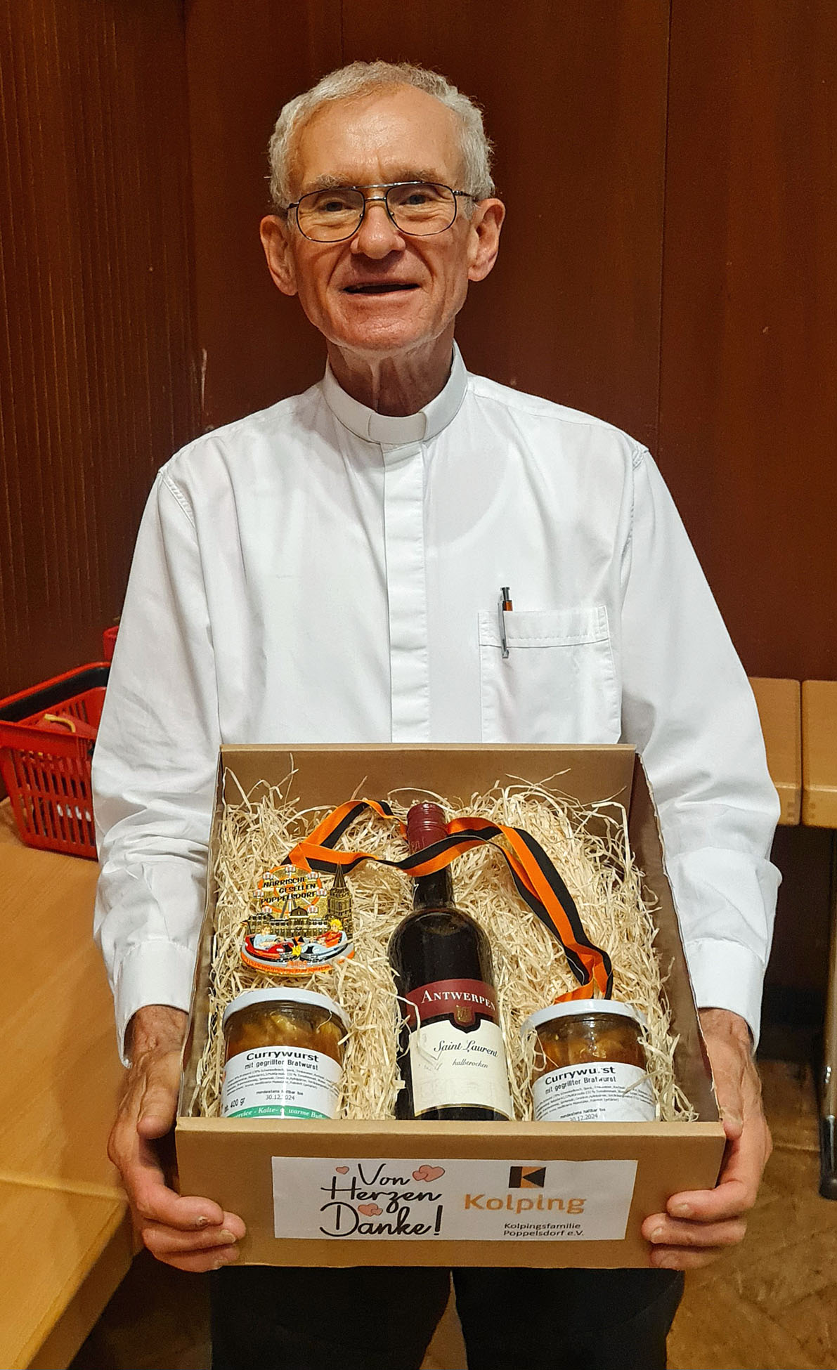 Als Dankeschön überreichte der Vorsitzende Karl-Heinz Kron Pfarrer Meurer einen Geschenkkarton für Currywurst, Rotwein und dem Karnevalsorden 2023 der Kolpingsfamilie Poppelsdorf